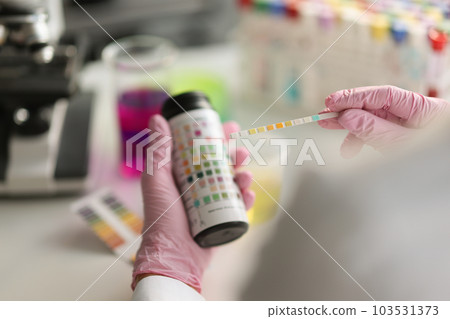 Doctor holds reagent strip for urinalysis closeup Doctor holds reagent strip for urinalysis closeup 103531373