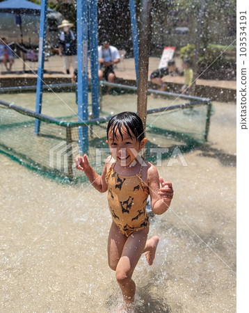 Girl playing in a park fountain 103534191