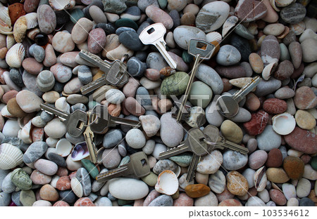 Lost metal keys scattered on smooth stones texture background Lost metal keys scattered on smooth stones texture background 103534612