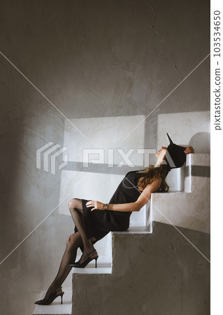 Woman in black laying on concrete stairs Woman in black laying on concrete stairs 103534650