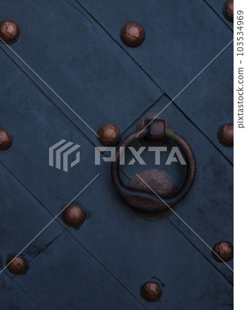 A strong black wooden door with heavy brown rivets 103534969
