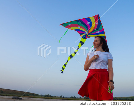 Colored kite against blue sky at sunset Colored kite against blue sky at sunset 103535258