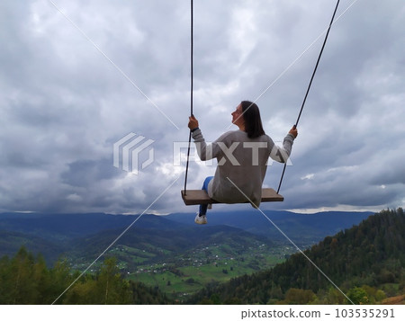 woman traveler enjoying of swinging on heavenly swing and mountain view woman traveler enjoying of swinging on heavenly swing and mountain view 103535291