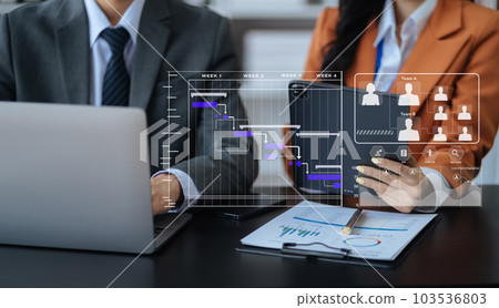 Businessman hand Project manager working and update tasks and Gantt chart scheduling virtual diagram.with smart phone, tablet and laptop in office. Businessman hand Project manager working and update tasks and Gantt chart scheduling virtual diagram.with smart phone, tablet and laptop in office. 103536803