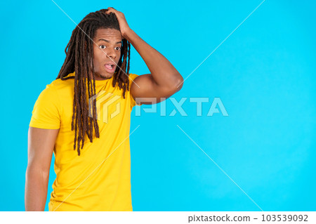 Man with dreadlocks with hand on face and thoughtful expression 103539092