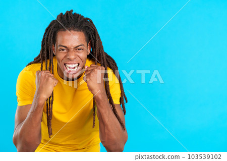Happy hispanic man with dreadlocks gesturing with fists while celebrating Happy hispanic man with dreadlocks gesturing with fists while celebrating 103539102
