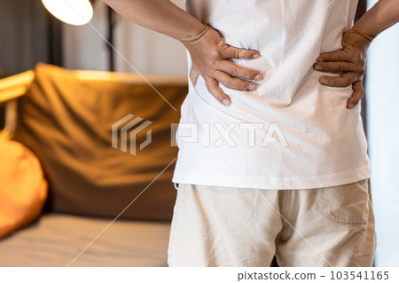 Back view of asian man having a backache,Stressed people suffering from waist pain,lumbar disc herniation,musculotendinous strain,touching low back pain with his hands,health care,medical concept 103541165