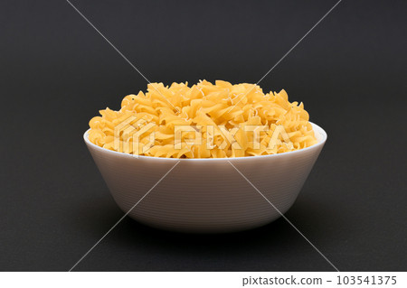Uncooked Fusilli Pasta in White Bowl on Wooden Board Uncooked Fusilli Pasta in White Bowl on Wooden Board 103541375