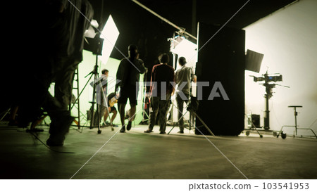Blurry images of film crew working and filming in video production studio which using equipments such as cinema camera big film light and soft box or light diffusion panel. TV Commercial Film industry 103541953