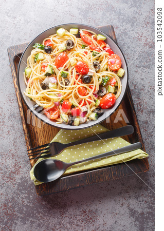 Vegetarian spaghetti salad with fresh vegetables and olives close-up in a bowl. Vertical top view Vegetarian spaghetti salad with fresh vegetables and olives close-up in a bowl. Vertical top view 103542098