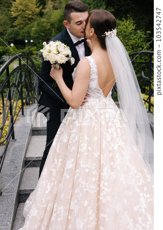 Pretty bride kid her groom, husband during wedding ceremony. Woman hold bouquet and hug groom 103542747