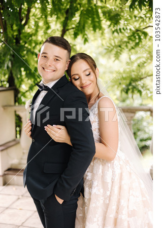 Portrait of newlyweds stand on balcony and dreaming. Handsome groom and beautiful bride on their wedding day 103542873