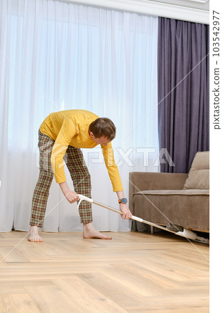 Middle age man mopping floors under the sofa Middle age man mopping floors under the sofa 103542977