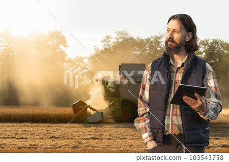 Farmer with digital tablet on a background of harvester. 103543758