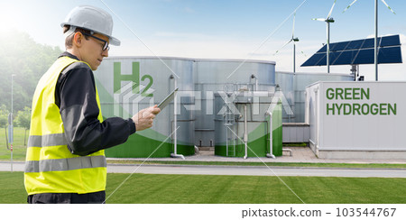 Engineer with tablet computer on a background of green Hydrogen factory. 103544767