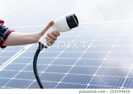 Electric vehicles charging plug on a background of solar panel 103544938