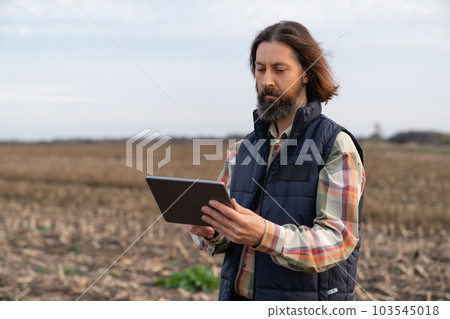 Farmer with digital tablet on an agricultural field. Smart farming and digital agriculture 103545018