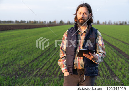Farmer with digital tablet in young wheat field. 103545029