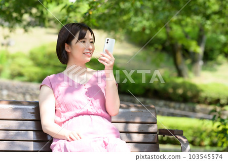 A young woman operating a smartphone in the shade A young woman operating a smartphone in the shade 103545574