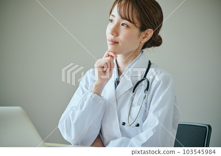 一位年輕的女醫生用手放在下巴上思考 一位年輕的女醫生用手放在下巴上思考 103545984