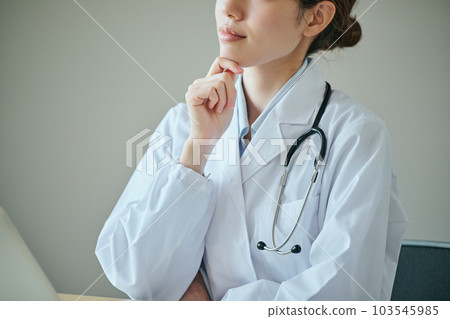 一位年輕的女醫生用手放在下巴上思考 103545985