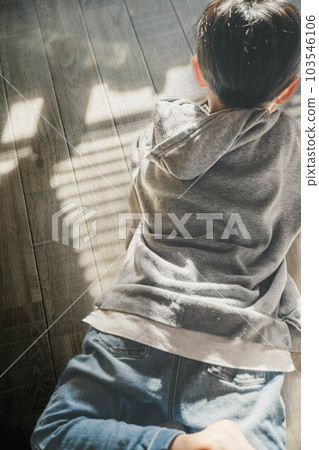A child touching his parent's smartphone by the window with the shadow of the blinds 103546106