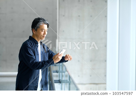 Business casual male engineer operating a smartphone in the office Business casual male engineer operating a smartphone in the office 103547597