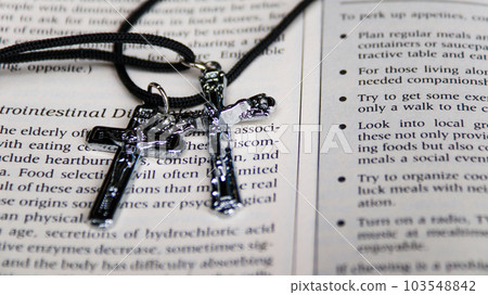 Shiny metal cross with black sling on old book to  recall the kindness of Jesus Christ for all of Christian 103548842