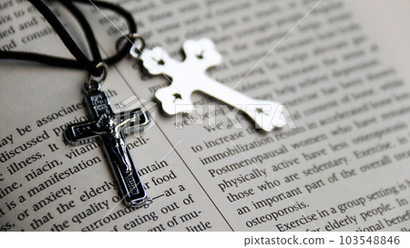 Shiny metal cross with black sling on old book to  recall the kindness of Jesus Christ for all of Christian Shiny metal cross with black sling on old book to  recall the kindness of Jesus Christ for all of Christian 103548846
