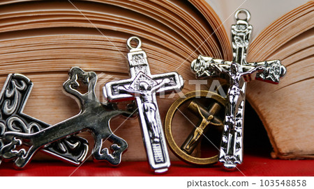 Shiny metal cross on old book to  recall the kindness of Jesus Christ for all of Christian                                103548858