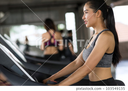 smiling Asian woman walk and run on treadmills in fitness gym 103549135
