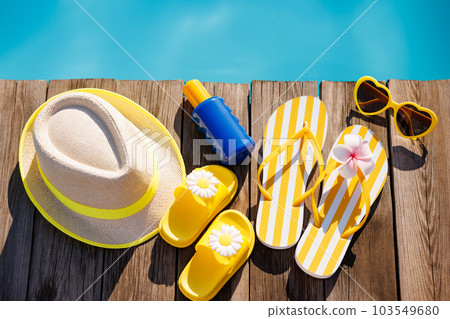 Beach hat, flip-flops and sunglasses on wooden planks near swimming pool 103549680