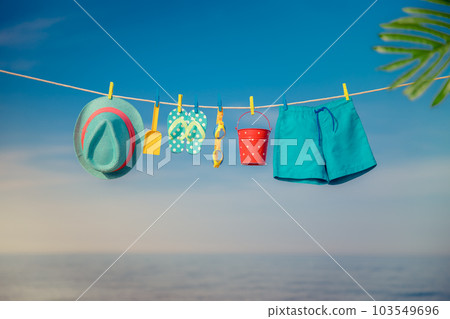 Beach hat, flip-flops and goggles hanging on a clothesline against sea and sky Beach hat, flip-flops and goggles hanging on a clothesline against sea and sky 103549696