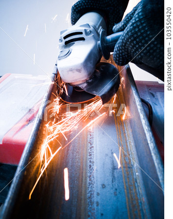 Worker cuts metal with abrasive disk 103550420