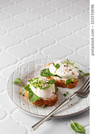 Poached egg sandwich with cream cheese, spinach and micro greens. Healty breakfast bruschetta on white tile background. Keto diet, text space for menu 103550696