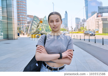 Young smiling teenage girl looking at camera on street of modern city Young smiling teenage girl looking at camera on street of modern city 103551586