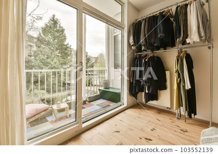 a room with clothes hanging on the wall and sliding glass door leading to an outside patio area that has wood flooring a room with clothes hanging on the wall and sliding glass door leading to an outside patio area that has wood flooring 103552139