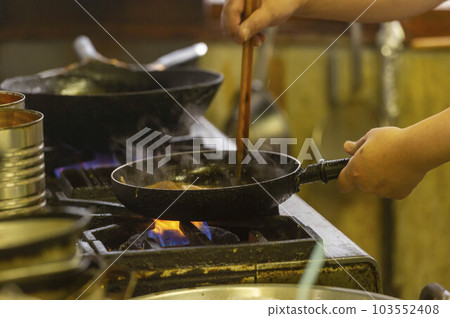 A scene of cooking with a frying pan on fire in the kitchen 103552408