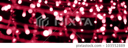 Blurry garland lights on a dark background. Festive Christmas and New Year background. Soft focus. Image toned in color of the year 2023 viva magenta Blurry garland lights on a dark background. Festive Christmas and New Year background. Soft focus. Image toned in color of the year 2023 viva magenta 103552889