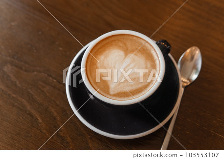 Coffee cup with a heart pattern in a blue cup on a wooden background Coffee cup with a heart pattern in a blue cup on a wooden background 103553107