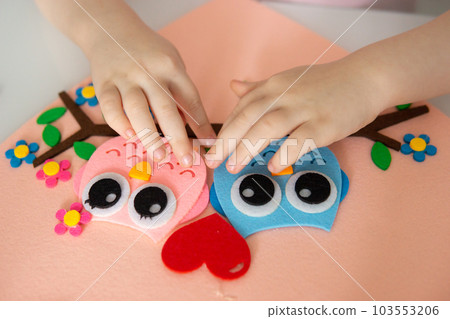 A blogger girl makes a felt craft for Valentine's Day in the shape of a heart. The concept of children's creativity and handmade. A blogger girl makes a felt craft for Valentine's Day in the shape of a heart. The concept of children's creativity and handmade. 103553206
