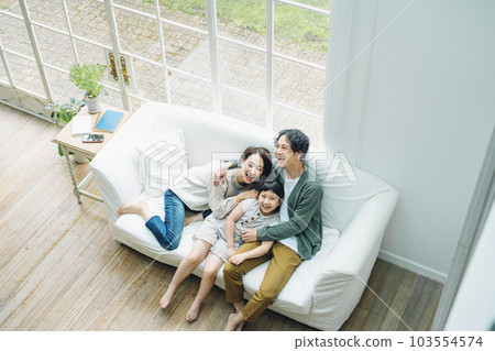 Portrait of a family sitting on a sofa in the living room at home 103554574