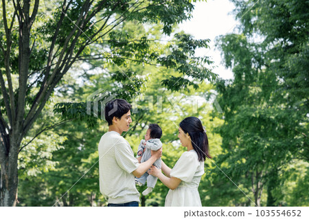 A couple holding a baby in the park 103554652