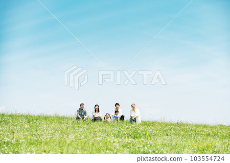 Portrait of a three-generation family sitting on a bank 103554724