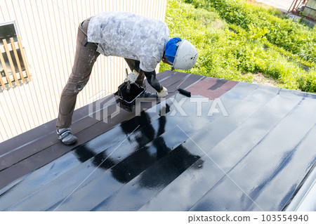 一位工匠正在為鐵皮屋頂上漆 103554940