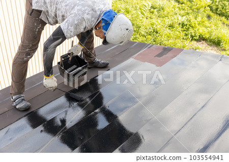 一位工匠正在為鐵皮屋頂上漆 103554941
