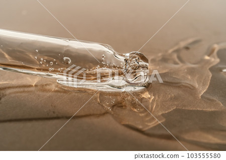 The texture of serum or oil with a pipette on a beige background. The texture of serum or oil with a pipette on a beige background. 103555580