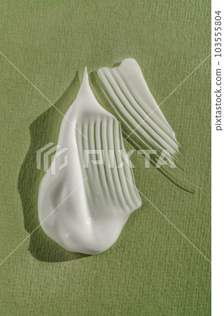 The texture of the white cream on a green background. The texture of the white cream on a green background. 103555804