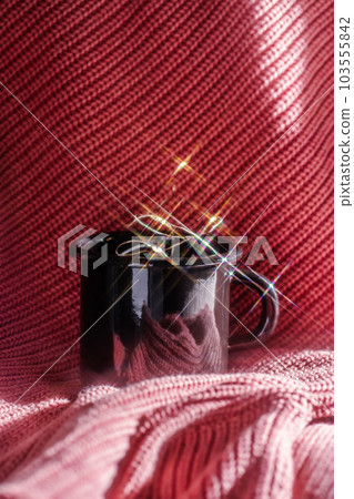 A mug with lights stands on a pink knitted background. A mug with lights stands on a pink knitted background. 103555842