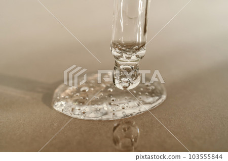 The texture of serum or oil with a pipette on a beige background. The texture of serum or oil with a pipette on a beige background. 103555844